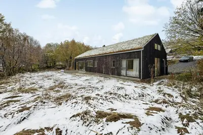 a house in a field with snow on the ground at Stylish Cabin Near Oppdal Ski Centre in Oppdal