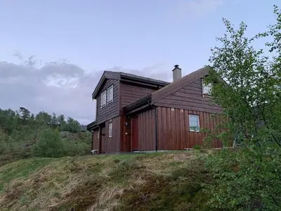 a wooden house sitting on top of a hill at Elegant Mountain Cabin With Kjerringafjell View in Brekka