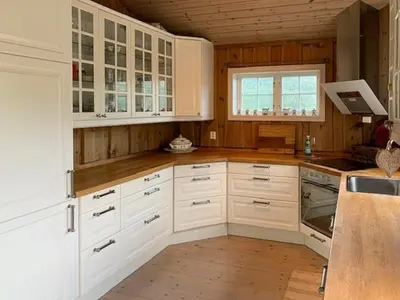a large kitchen with white cabinets and a window at Elegant Mountain Cabin With Kjerringafjell View in Brekka