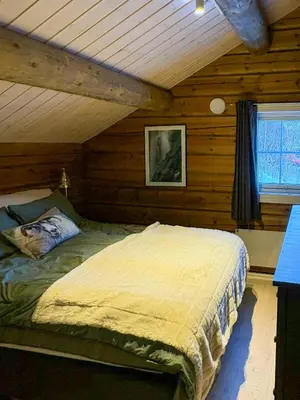 a bedroom with a bed in a log cabin at Timber Cabin With Outdoor Spa Near Stranda in Brunstad