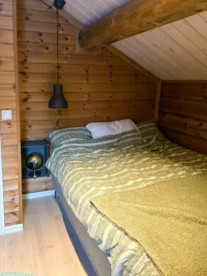 a bedroom with a bed in a wooden cabin at Timber Cabin With Outdoor Spa Near Stranda in Brunstad