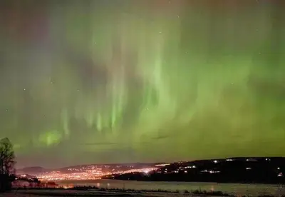 an aurora in the sky over a city at Antique House With Lake View Near Lillehammer in Fryjordet