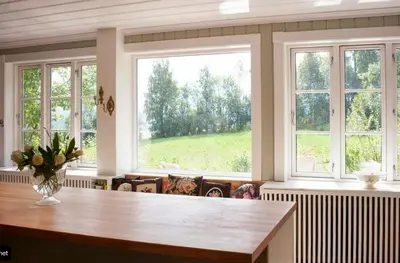 a large kitchen with windows and a wooden table at Antique House With Lake View Near Lillehammer in Fryjordet