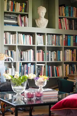a book shelf filled with books and a table with flowers at Antique House With Lake View Near Lillehammer in Fryjordet