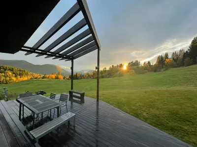 a deck with a table and benches on a field at Villa Vetleskog On Mollandsmarki In Sogn in Hafslo