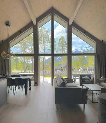 a living room with couches and a table and windows at Modern Cabin For Large Families In Oppdal in Oppdal