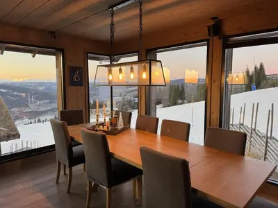 a dining room with a table and chairs and windows at Beautiful Ski-in Ski-out Cabin at the top of the mountain in Hafjell in Hafjell
