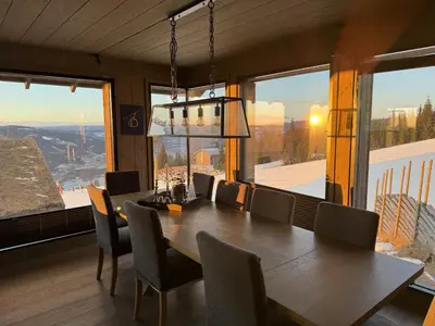 a dining room with a table and chairs and a large window at Beautiful Ski-in Ski-out Cabin at the top of the mountain in Hafjell in Hafjell