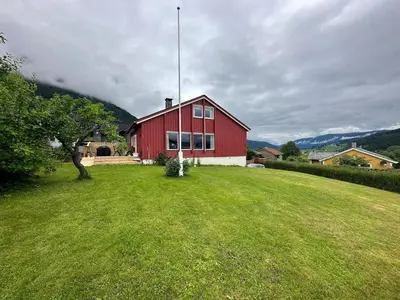 a red house on a grassy yard with a tree at Perfect family house in Voss in Vossevangen