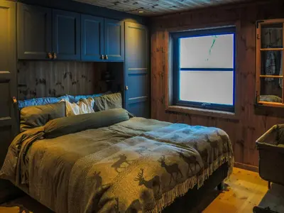 a bedroom with a bed with blue cabinets and a window at Cabin With Sauna And Views Over Hallingdal in Flå