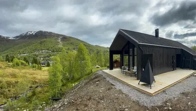 a house with a black roof and a wooden deck at Cabin With Ski-Inski-Out At Stranda Ski Resort in Stranda