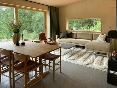 a living room with a table and a couch at Architect-Designed Cabin By Lake With Sauna