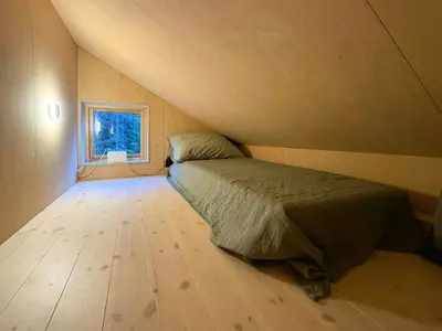 a small bedroom with a bed and a window at Architect-Designed Cabin By Lake With Sauna