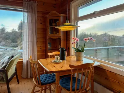 a dining room with a table and chairs and a window at Cabin On Hilltop With Beach And Sea Views in Bekkjarvik