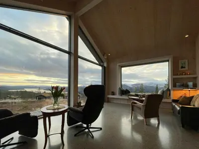 a living room with a table and chairs and large windows at Eco-Friendly Cabin With Panoramic Views In Savalen in Tynset