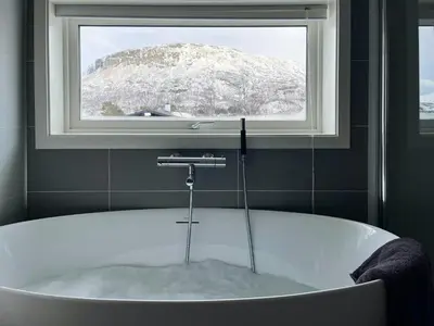 a bath tub in a bathroom with a window at Moderne Og Koselig Hytte På Hardangervidda in Garden