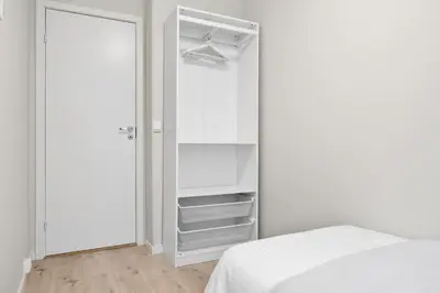 a white bedroom with a bed and a closet at Central stay apartment - Rosenberg in Bergen