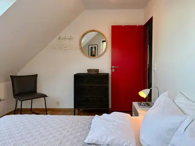 a bedroom with a red door and a chair at House With 90 Metres Private Beach On Bømlo in Ervik