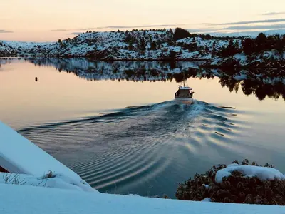 a boat floating on a lake in the snow at House With 90 Metres Private Beach On Bømlo in Ervik