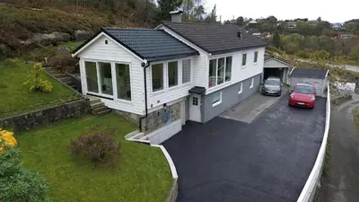 a white house with a car parked in a driveway at Fjordclaw SNM- Cozy & Premium Feel in Bergen