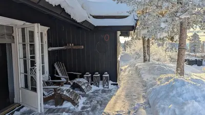a house covered in snow with two chairs and a table at Fjellhytte med boblebad og utsikt på Blefjell in Flesberg