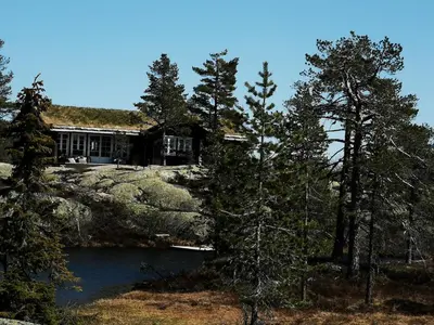 a house sitting on top of a hill next to a lake at Fjellhytte med boblebad og utsikt på Blefjell in Flesberg