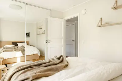 a bedroom with white walls and a large mirror at City apartment with balcony and 3 bedrooms! in Bergen