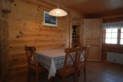 a dining room with a table and chairs in a log cabin at Leilighet på fjellet nær Geilo in Hol