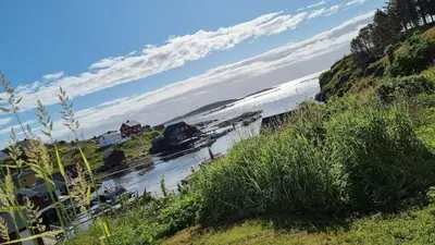 a boat in a body of water next to a hill at Mausund- Øyperla i havet! Egen båtplass ved hytta! in Frøya