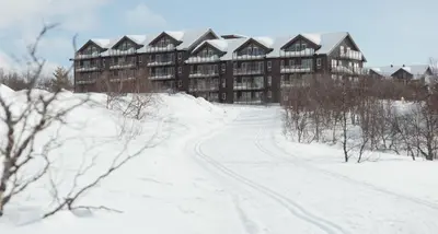 a building in the snow with a road in front at Kikut1010 Skurdalsvegen 107 in Hol