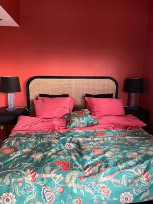 a bed with red walls and pink pillows and a cat on it at Cottage With Sunny Terraces And Sea Views in Lysøysund