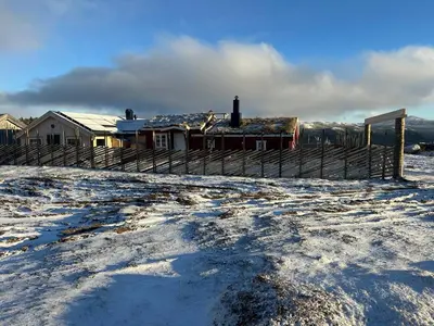 a snow covered yard with a house and a fence at Sits in the middle of Reinheimen and Dovrefjell Rondane in Dombås