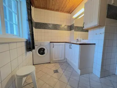 a laundry room with a washing machine and a stool at Idyllisk feriested in Gol