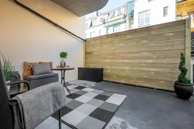 a patio with a wooden fence and a chair and a table at Spacious 2-room in the city center, easy access to everything in Ålesund