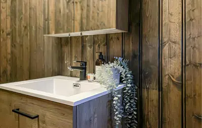 a bathroom with a white sink and wooden walls at Lovely Home In Sjusjøen With Sauna in Sjusjøen