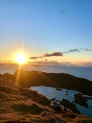 a sunset on the top of a mountain with a lake at Spacious house with a beautiful view for rent in Ålesund