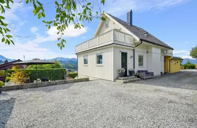 a white cottage with a gravel driveway at Spacious house with a beautiful view for rent in Ålesund