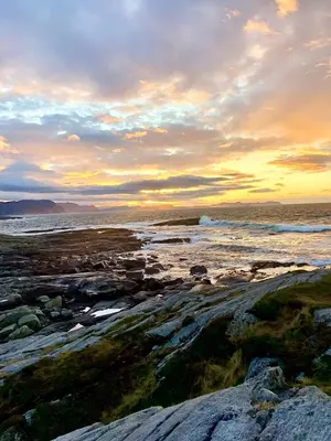 a sunset on a rocky beach with the ocean at Spacious house with a beautiful view for rent in Ålesund