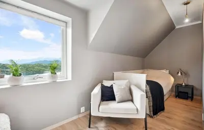 a bedroom with a bed and a chair and a window at Spacious house with a beautiful view for rent in Ålesund