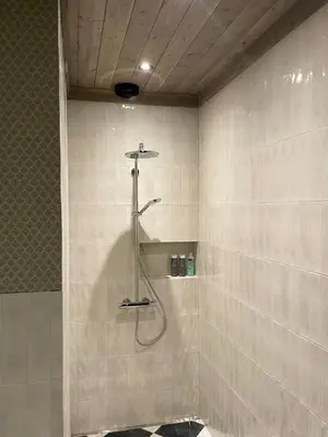 a shower in a bathroom with white tiles at Modern Farm With Panoramic Views And Nature in Bjorli