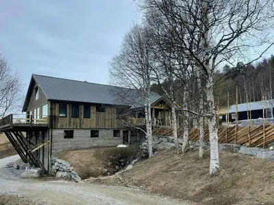 a large wooden house on a hill with trees at Modern Farm With Panoramic Views And Nature in Bjorli