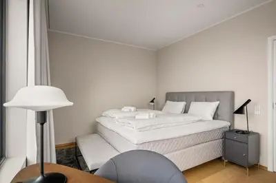a white bedroom with a bed and a desk at Bellevue Penthouse - Exclusive Design in Bergen