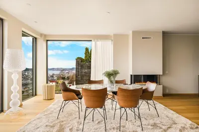 a dining room with a table and chairs and a large window at Bellevue Penthouse - Exclusive Design in Bergen