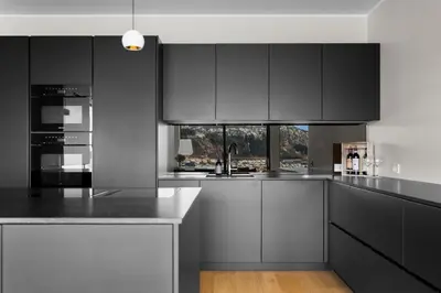 a kitchen with white cabinets and black appliances at Bellevue Penthouse - Exclusive Design in Bergen