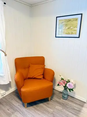 an orange chair in a room with a vase of flowers at Pellan in Surnadal