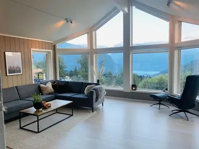 a living room with a blue couch and large windows at High standard, large cabin with amazing view in Stryn
