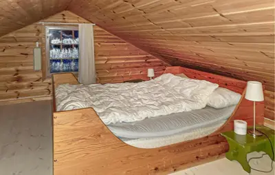 a bed in a log cabin with a window at Beautiful Home In Lampeland With Sauna in Lampeland