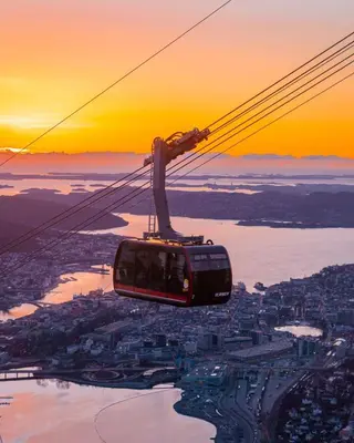 a cable car flying over a city at sunset at Beautiful apartment in the heart of Bergen in Bergen