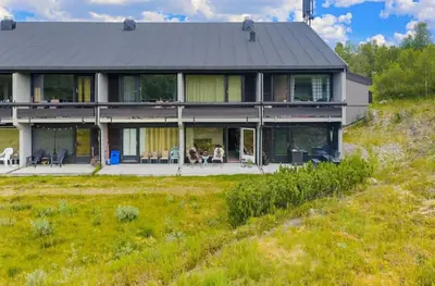 a house on a hill with people sitting on the porch at Leilighet på Hovden in Bykle