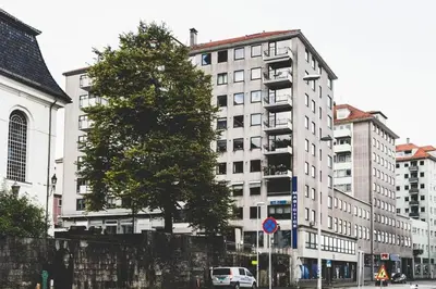 a tree in front of a tall white building at Ultra central flat with balcony in Bergen